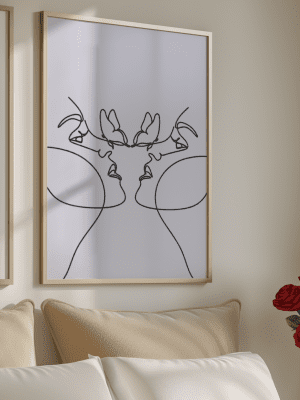 Framed minimalist one-line art print showing two abstract faces in profile and two butterflies on a white background, hanging above a couch.