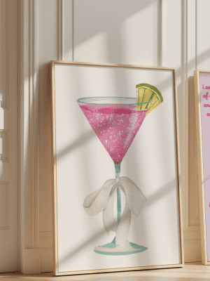 Framed pink cocktail art print displayed in a stylish home setting.