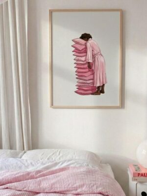 A peaceful illustration print shows a Black woman in a pink robe asleep and leaning against a tall, leaning stack of pink pillows.